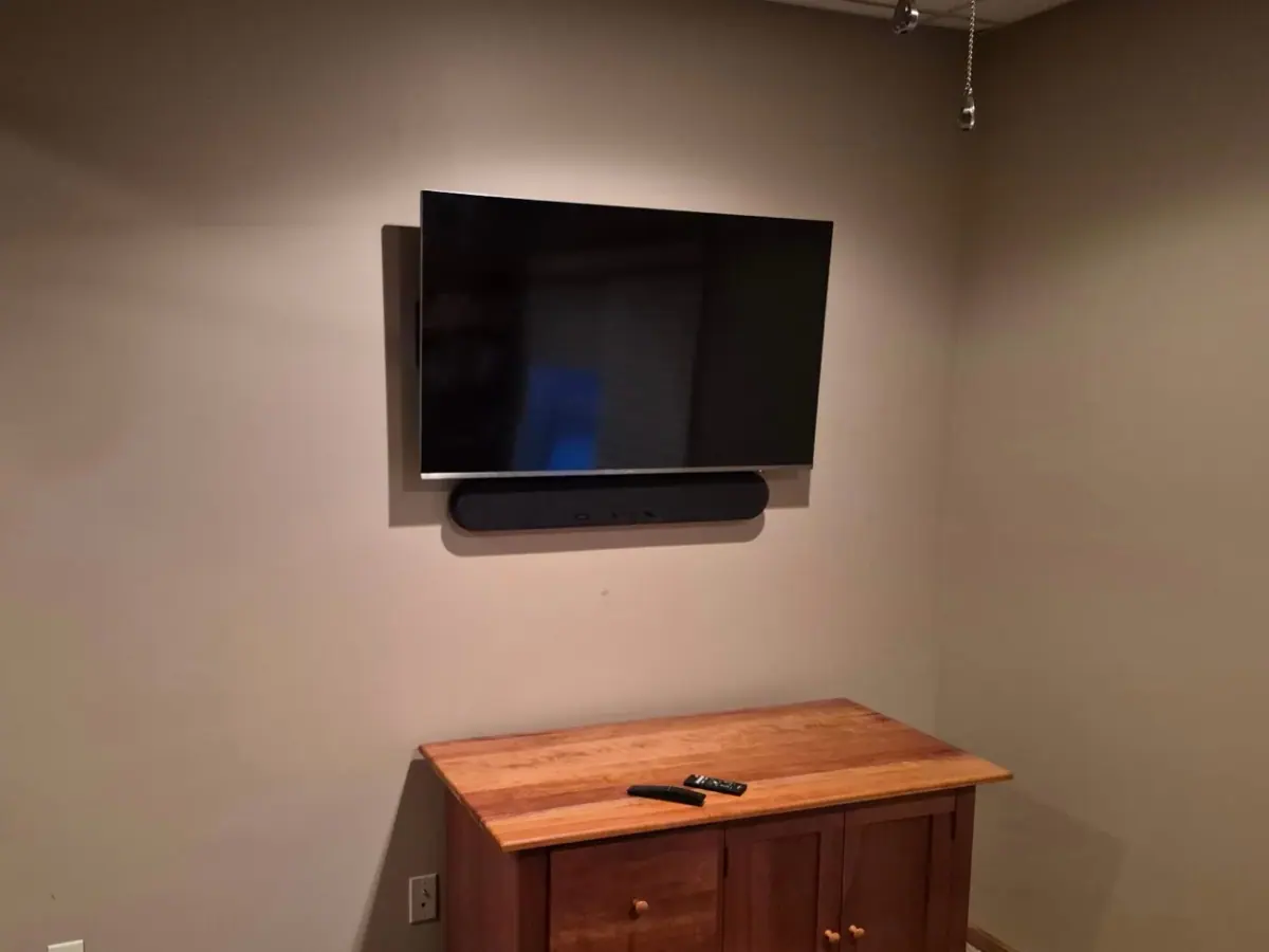 43-inch TV with soundbar mounted on drywall with tilt bracket and in-wall cord concealing
