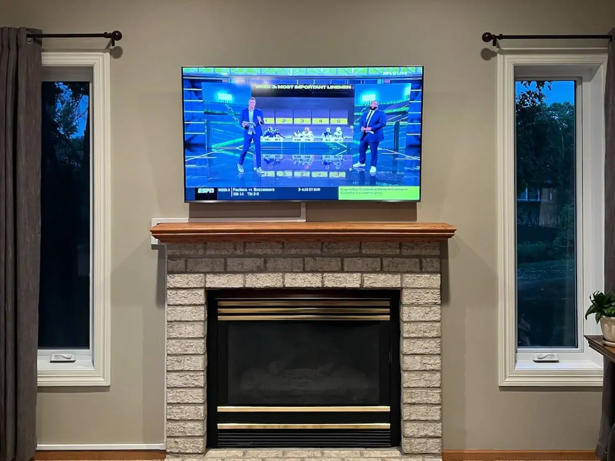 55-inch TV mounted above brick fireplace in Plymouth with exterior cord concealing