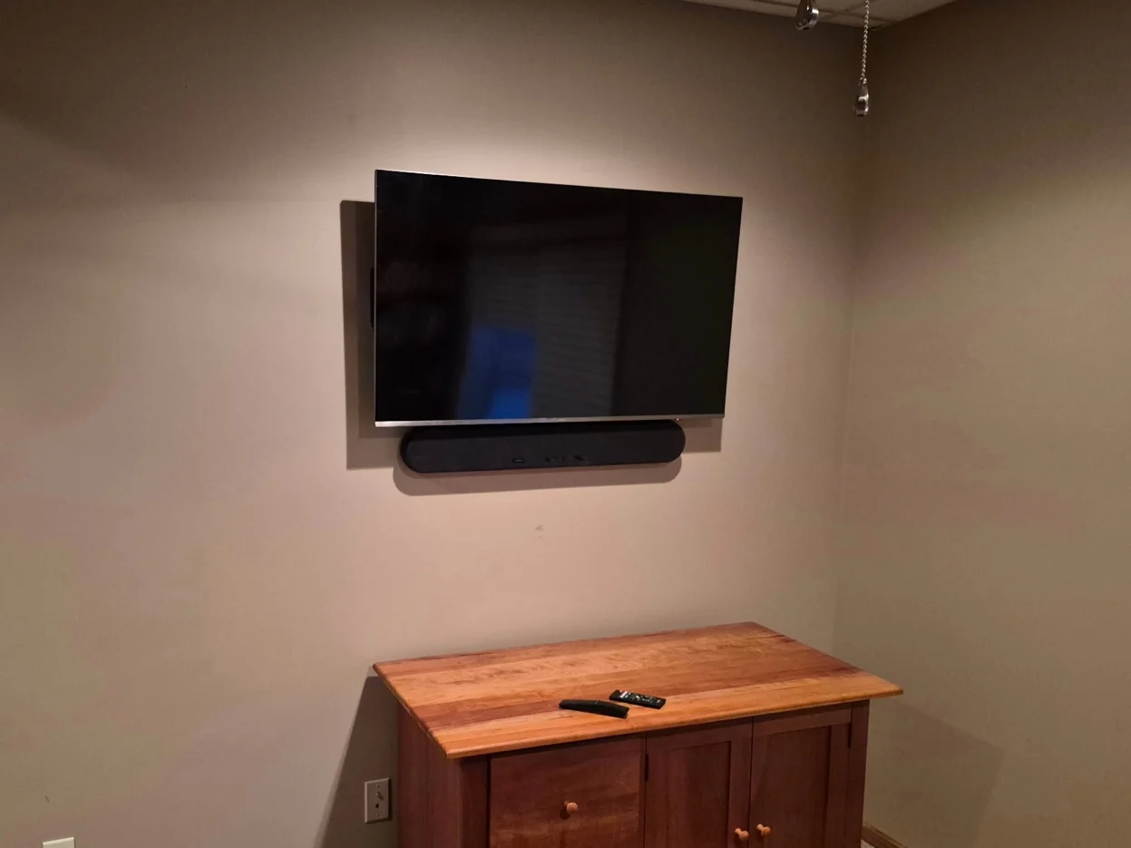 43-inch TV with soundbar mounted on drywall with tilt bracket and in-wall cord concealing