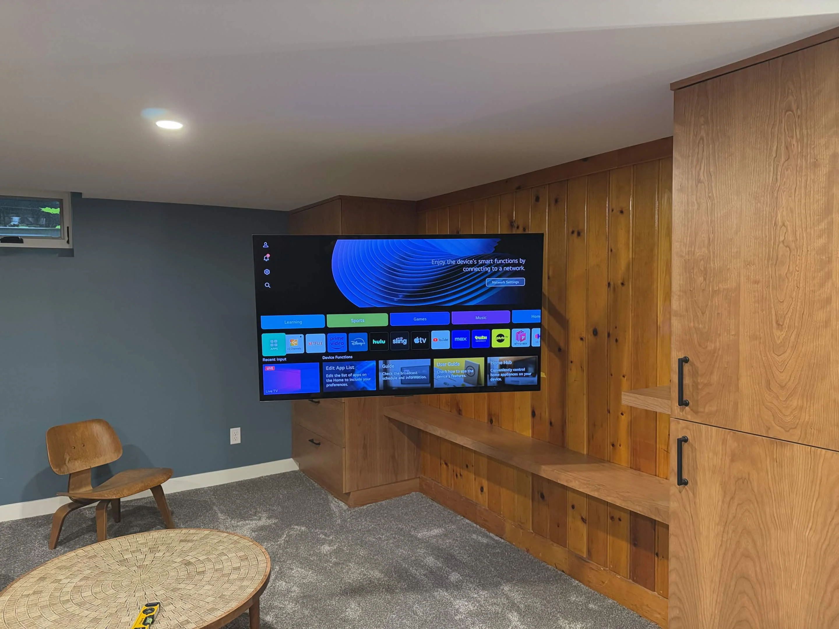 55-inch TV mounted on wood-paneled wall in a renovated St. Paul basement with an extended full-motion bracket