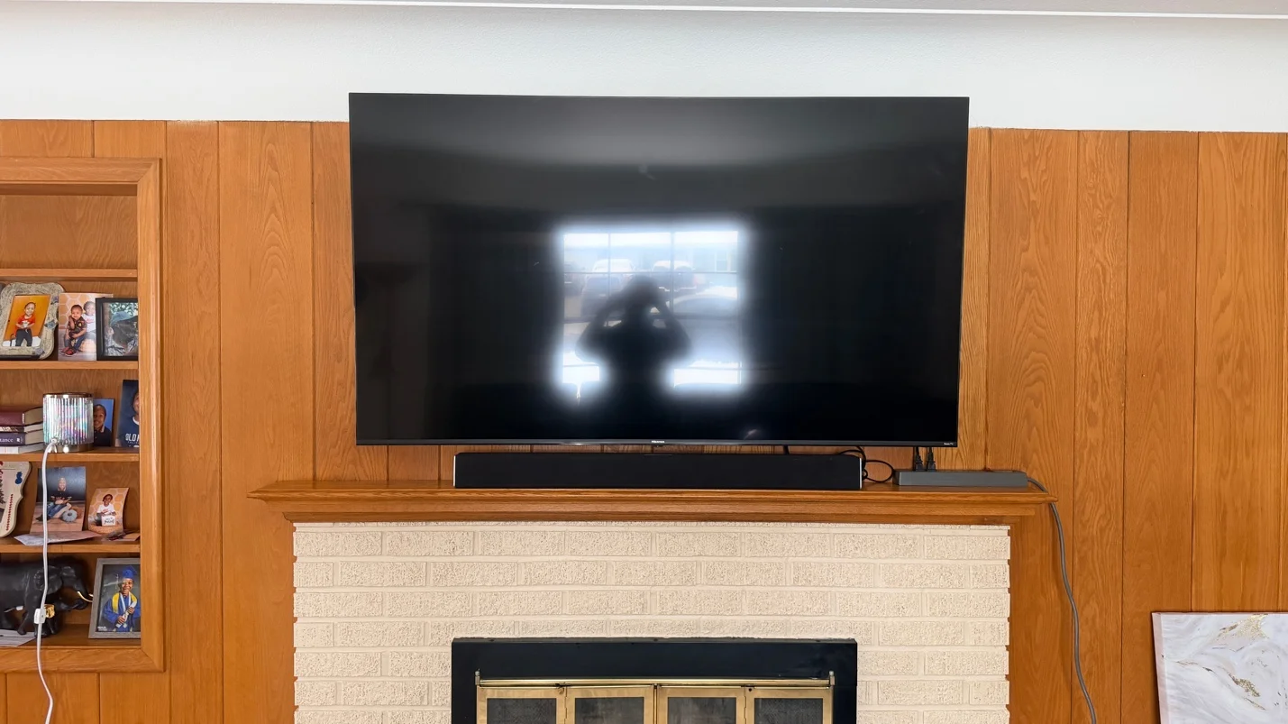 65-inch TV mounted on wood slat accent wall above brick fireplace